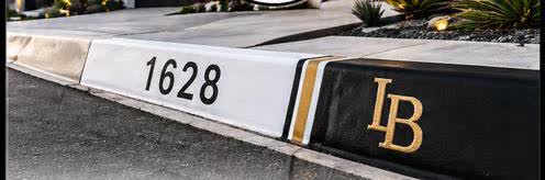 Hand-painted curb showing house number 1628 with a gold LB monogram, freshly finished.